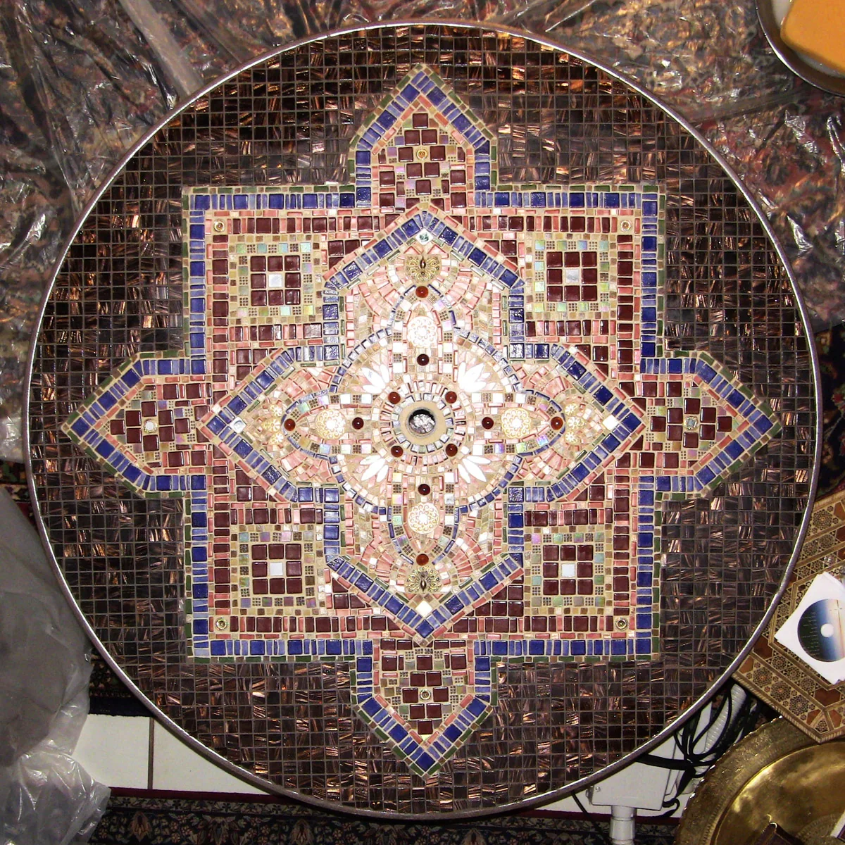 Arabesque: a round table top with an eight-pointed star mosaic in cobalt, burgundy, rose and gold glass on a field of copper tiles